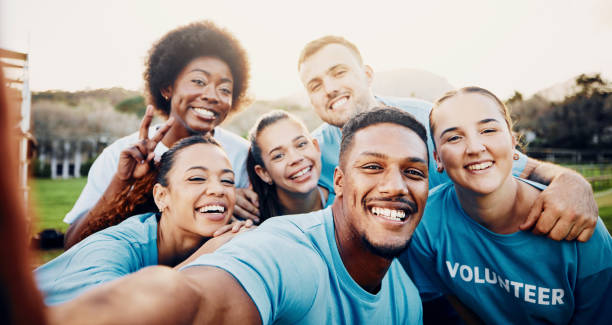 A group of volunteers in matching shirts smiling together outdoors.